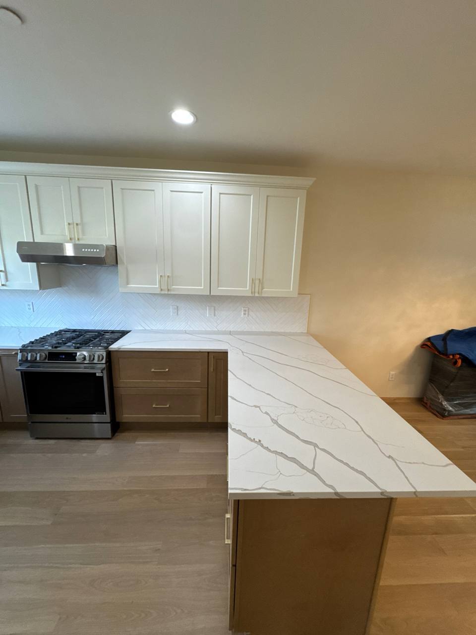 Kitchen remodel with white shaker cabinets, quartz countertops, and herringbone backsplash